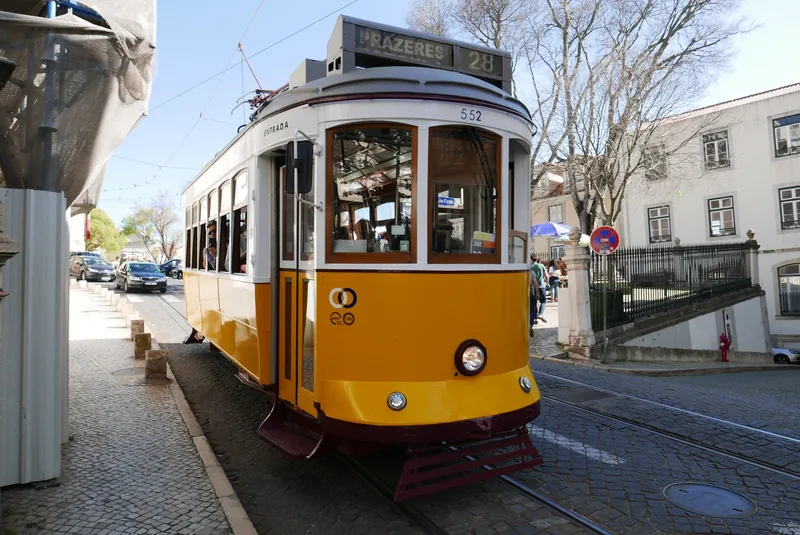 Xe điện màu vàng số 28 hướng đến Prazeres trên con đường lát đá cuội ở Lisbon.