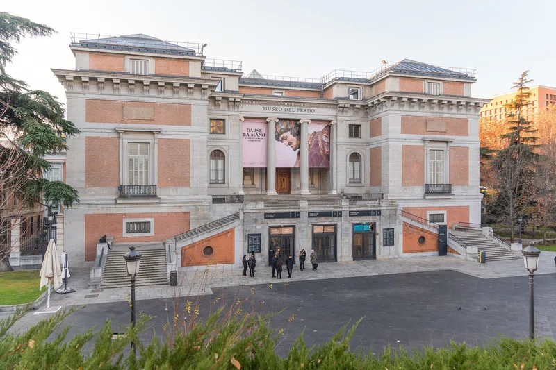 Mặt tiền kiến trúc cổ điển của Bảo tàng Prado với các tấm banner phía trên lối vào ở Madrid