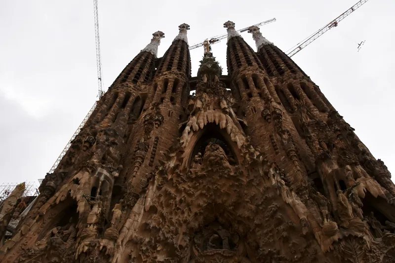 Những tháp nhọn chạm khắc tinh xảo của vương cung thánh đường Sagrada Família vươn lên dưới bầu trời nhiều mây ở Barcelona.