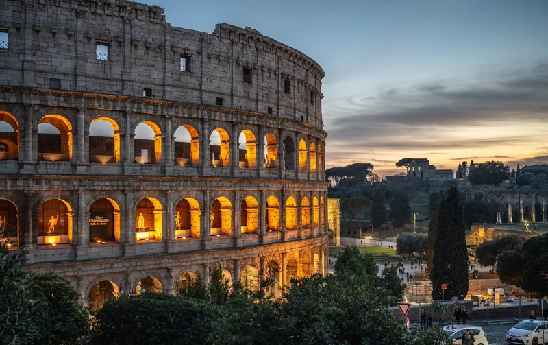 Những mái vòm của đấu trường Colosseum sáng đèn rực rỡ dưới hoàng hôn ở Rome.