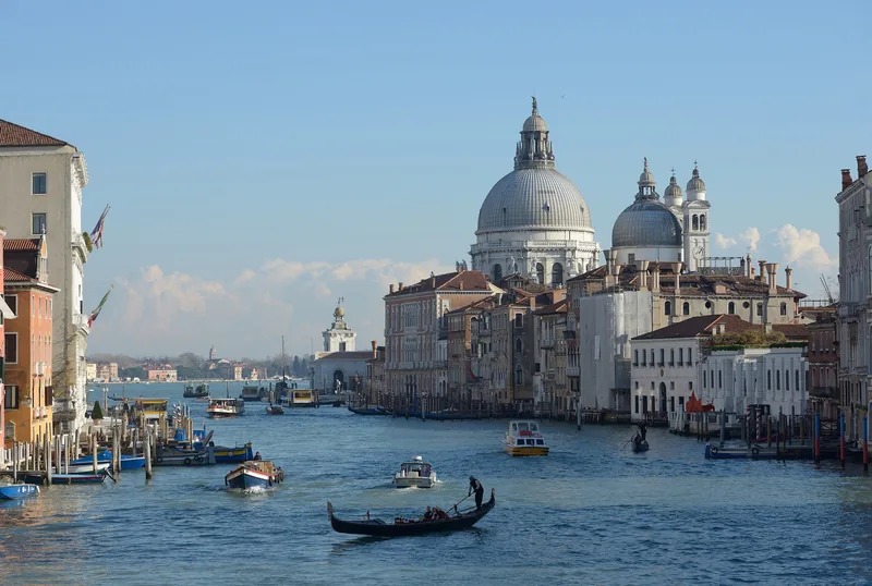 Một thuyền gondola và tàu thuyền lướt trên kênh Grand Canal của Venice dưới vương vòm nhà thờ Santa Maria della Salute.