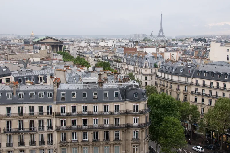 Toàn cảnh mái nhà Paris nhìn từ trên cao với tháp Eiffel thấp thoáng phía xa.