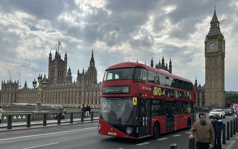 Xe buýt hai tầng màu đỏ băng qua cầu Westminster với tháp Big Ben và tòa nhà Quốc hội phía sau ở London.