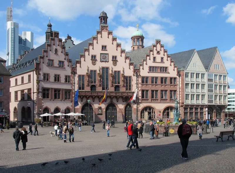 Những tòa nhà cổ có mái bậc thang bao quanh quảng trường Römerberg ở Frankfurt, du khách dạo bước trên nền đá cuội.