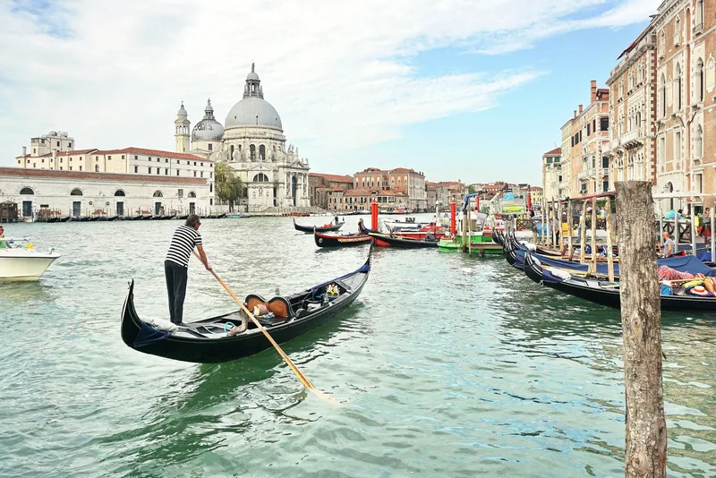 Người chèo gondola trên kênh Grand Canal ở Venice, phía sau là nhà thờ Santa Maria della Salute.