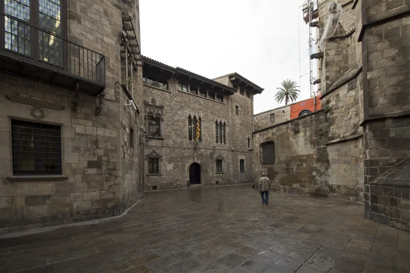 Một người đi bộ lặng lẽ băng qua quảng trường đá yên tĩnh ở Khu Gothic, Barcelona.