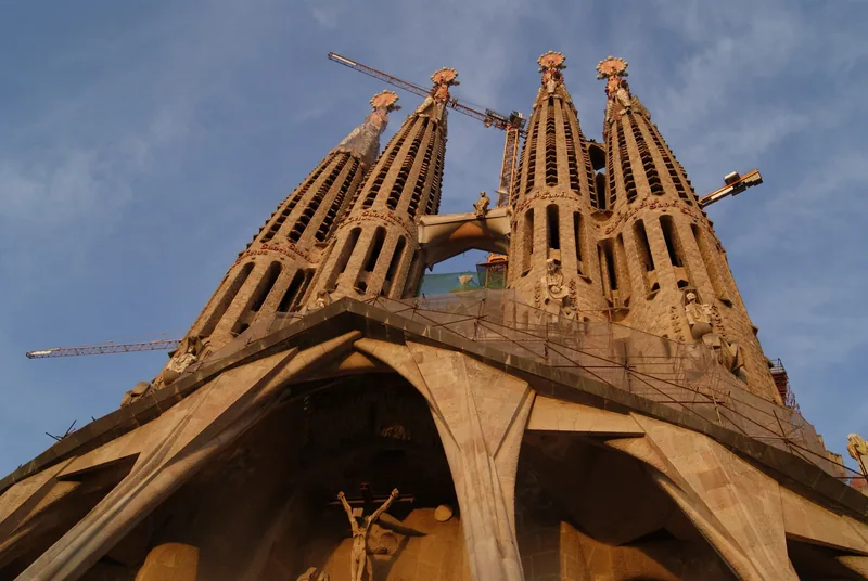 Những tháp cao của Sagrada Família ở Barcelona vươn lên trời xanh với các cần cẩu xây dựng gần đó.