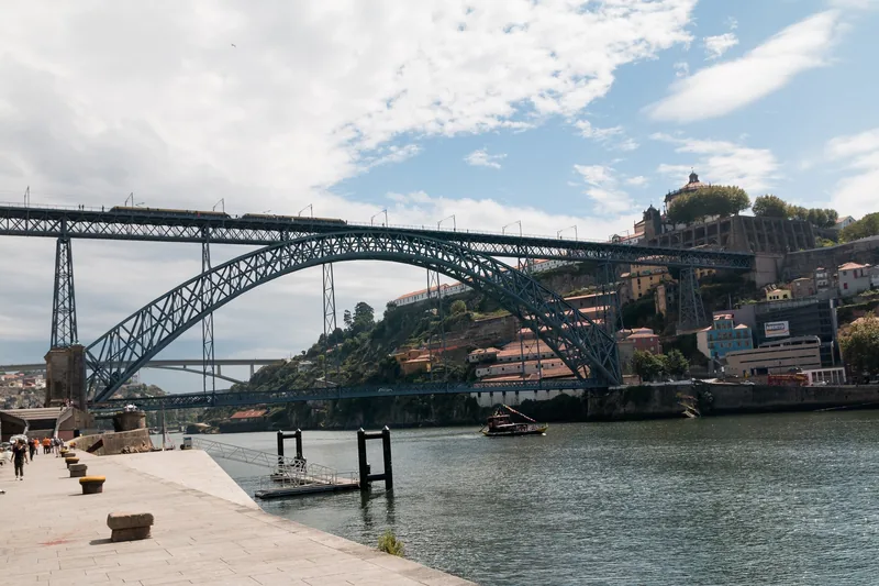 Cây cầu sắt Dom Luís I vươn cánh cung qua sông Douro, phía sau là những ngôi nhà trên đồi của Porto.